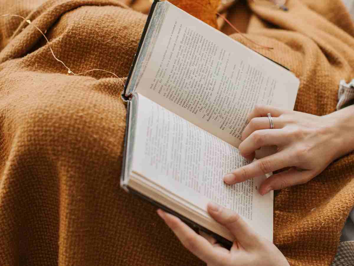 donna legge libro con una coperta sulle gambe