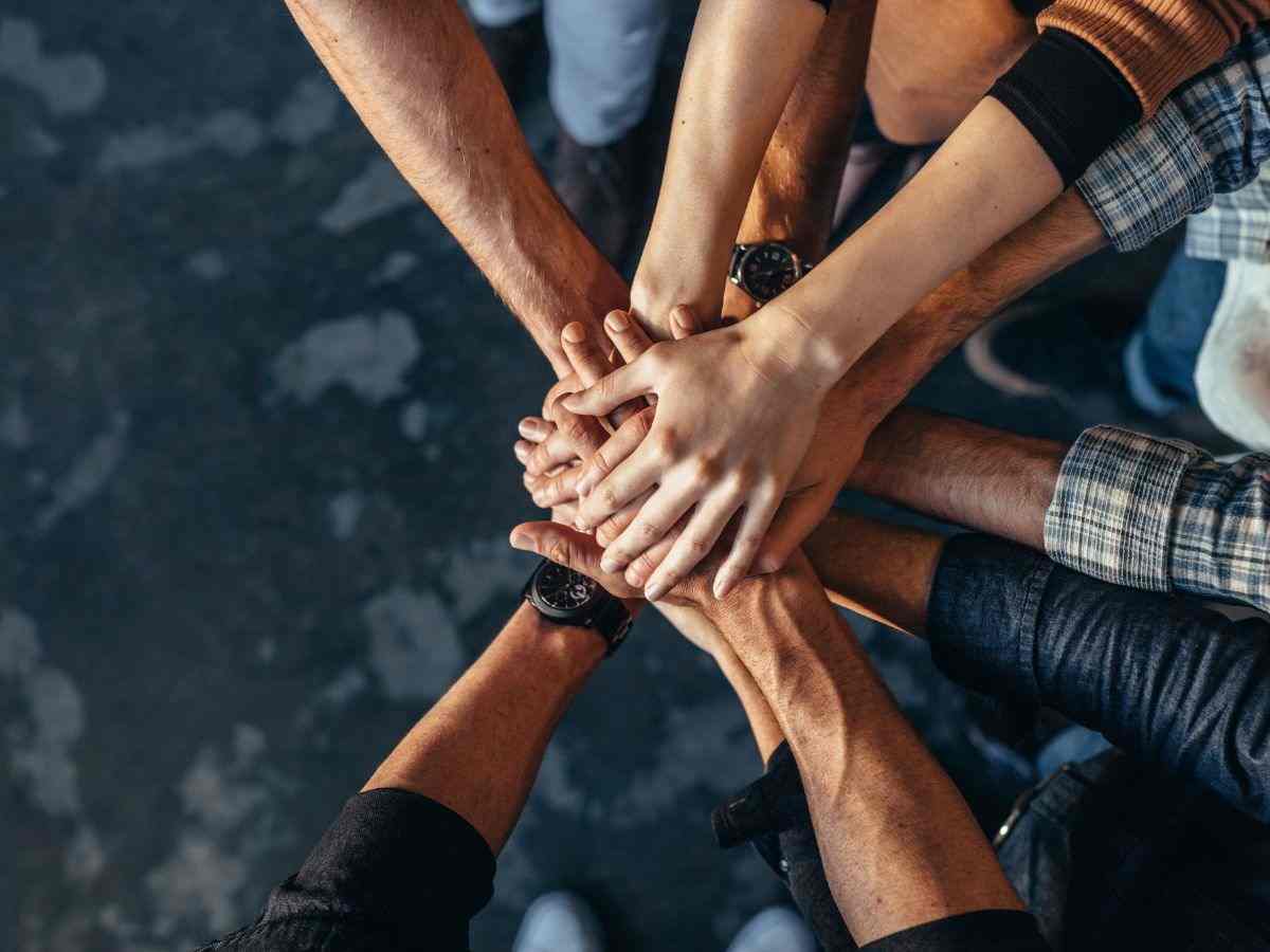 persone uniscono le mani in centro