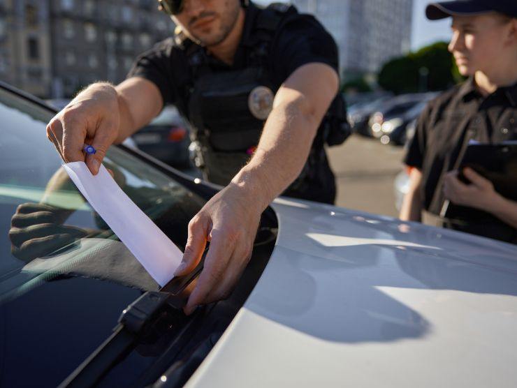 polizotti che lasciano multa sul parabrezza auto