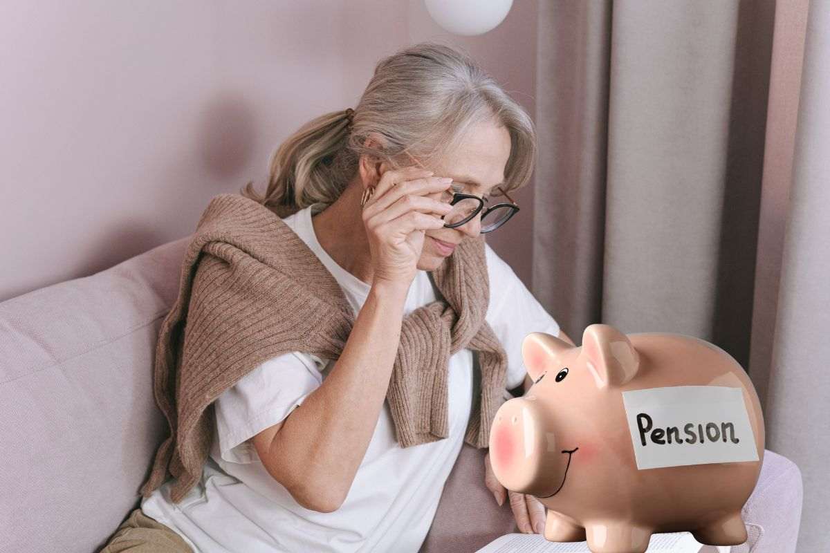 donna matura che legge e salvadanaio con scritta pensione